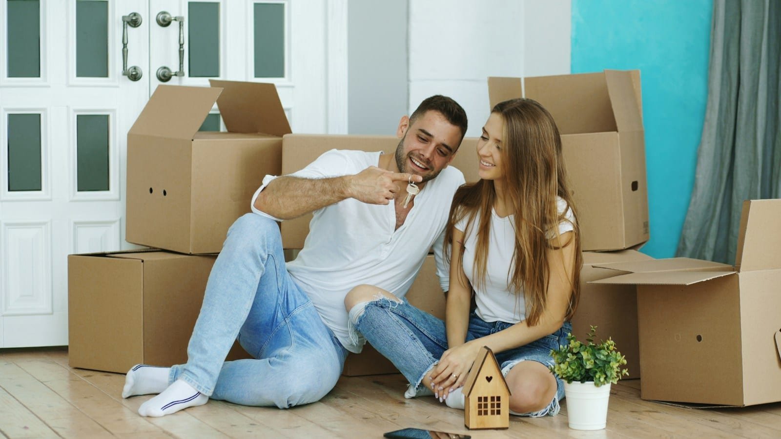 Déménagement de particuliers : s'installer sereinement Couple assis par terre au milieu de cartons de déménagement dans leur nouveau logement