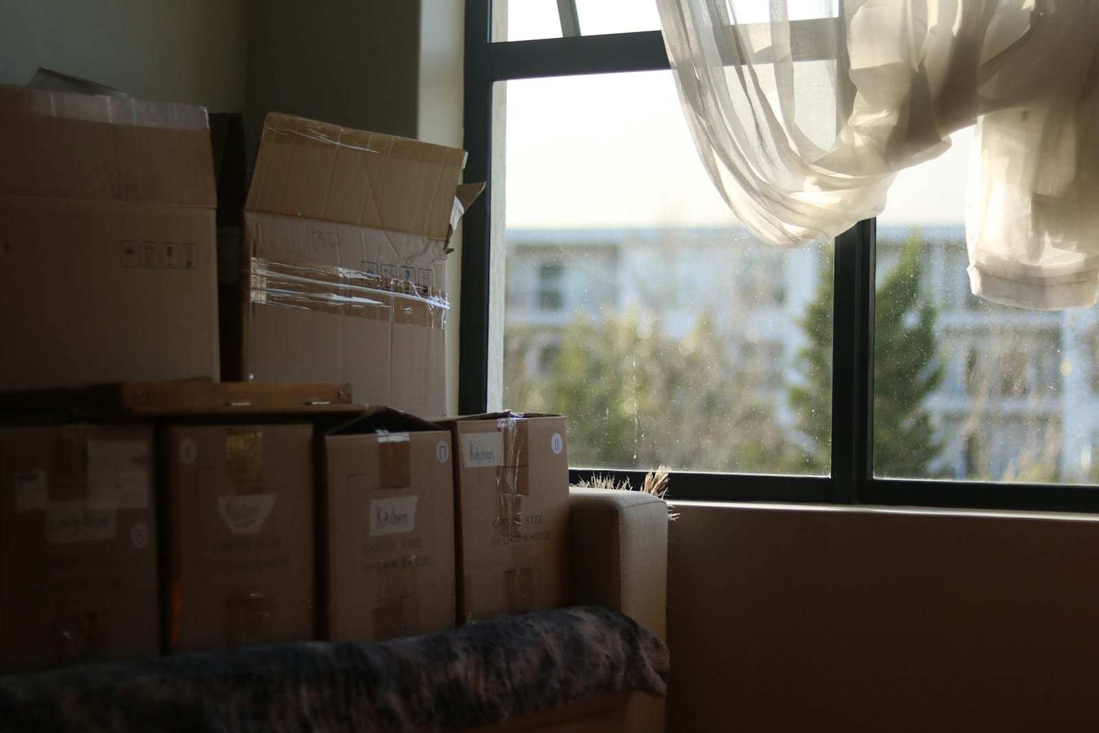Déménagement étudiant : petit volume, organisation simple Chambre lumineuse encombrée de cartons de déménagement empilés près d'une fenêtre