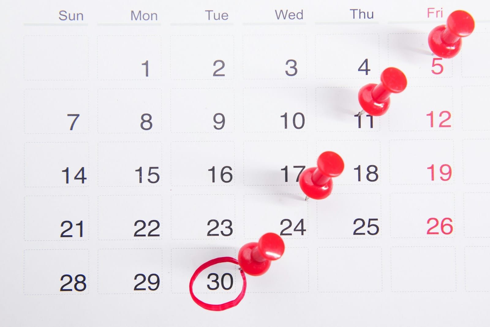 Calendrier mensuel sur lequel plusieurs dates sont marquées de punaises rouges