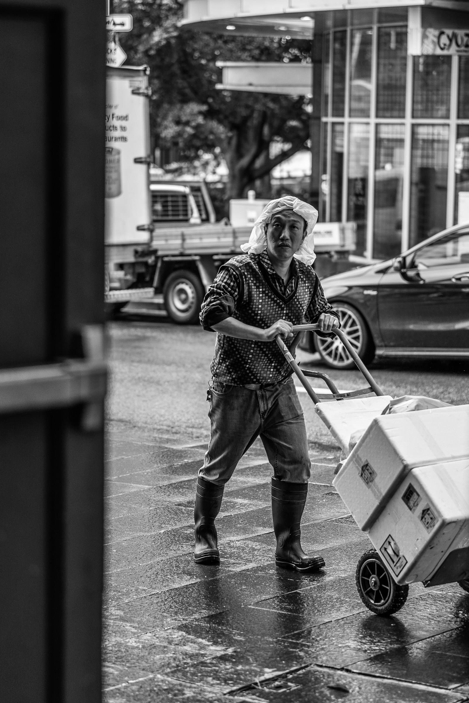 Transport d'objets lourds : le bon matériel pour chaque charge Personne poussant un diable chargé d’un carton dans une rue, photo en noir et blanc