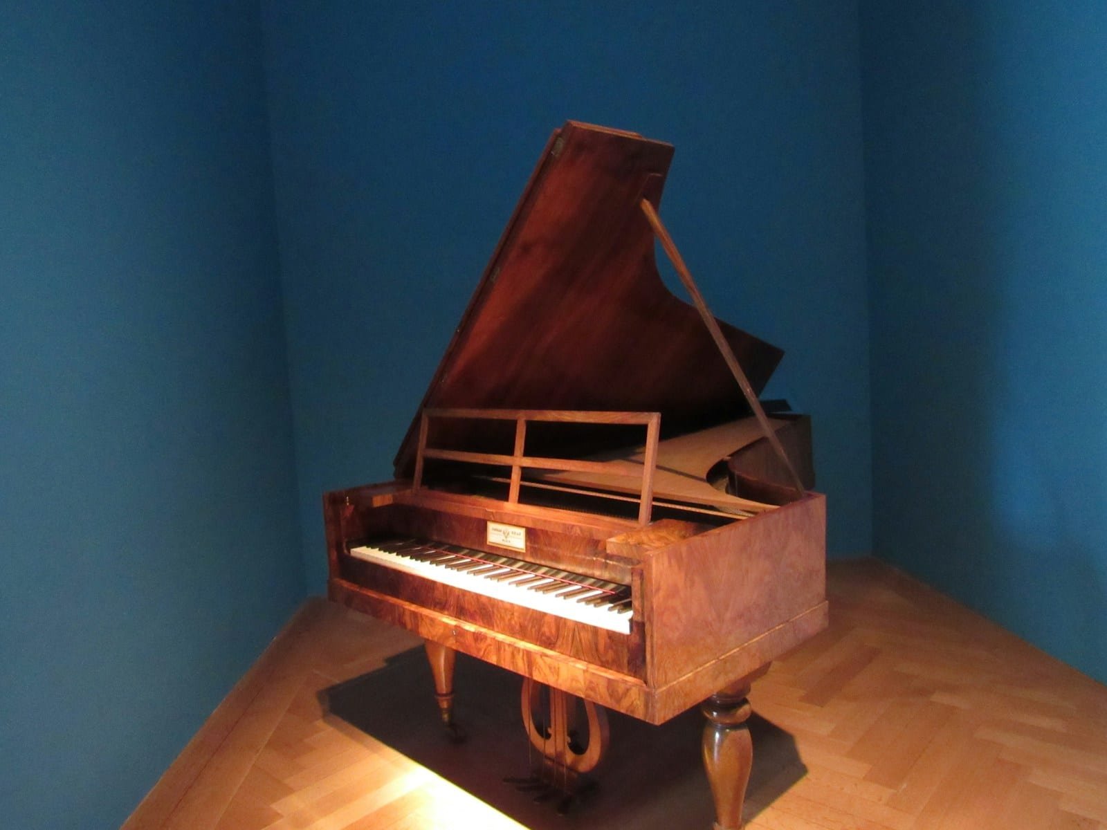 Transport spécialisé : des objets précieux, une manutention dédiée Piano ancien en bois précieux, couvercle ouvert, dans une pièce aux murs bleus